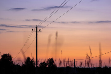 Silhouette of electric pole on meadow at sunset. Electricity, nature, sunset concept.