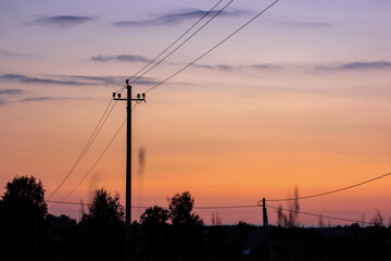 Silhouette of electric pole on meadow at sunset. Electricity, nature, sunset concept.