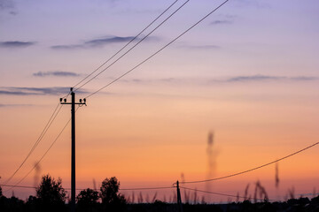 Silhouette of electric pole on meadow at sunset. Electricity, nature, sunset concept.