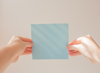  Blue square leaflet with hard shadows mock up on a white background in the hand of a young woman. School concept