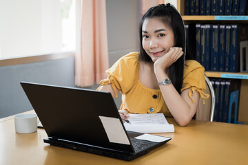 A teenager student studies online via laptop. University student girl watches online classes and writing a syllabus in a notebook. Concept of distance study, online learning, webinars. Stock photo.