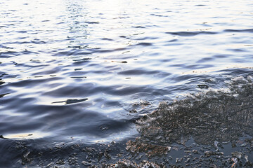 Abstract natural blurred water surface with ice remnants in spring at sunset.