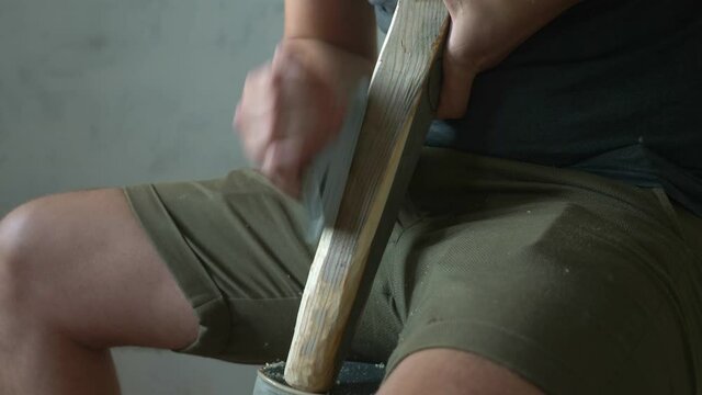 man planes a planer wooden bar sitting indoors. closeup
