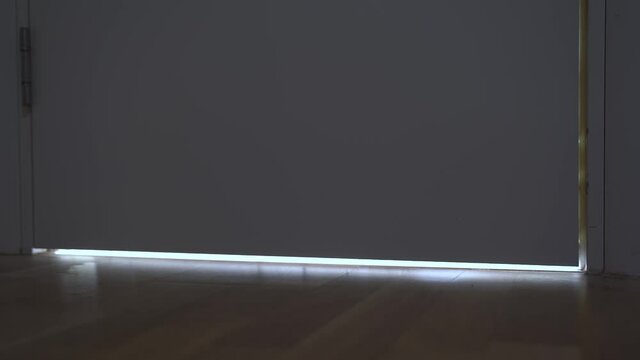 Light comes on in slit under closed door and you can see moving shadows reflected on floor surface. Illegal entry of strangers or burglars and criminals into home.