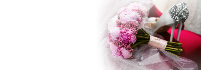 Elegant wedding accessories of an attractive bride. Wedding rings, shoes, bridal bouquet, floral arrangements, veil. Copy space for text. Background for greeting card or invitation.