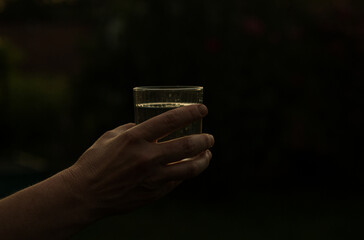 Sometimes a glass of water saves lives. A glass of water in the human hand in the sunset. Life...