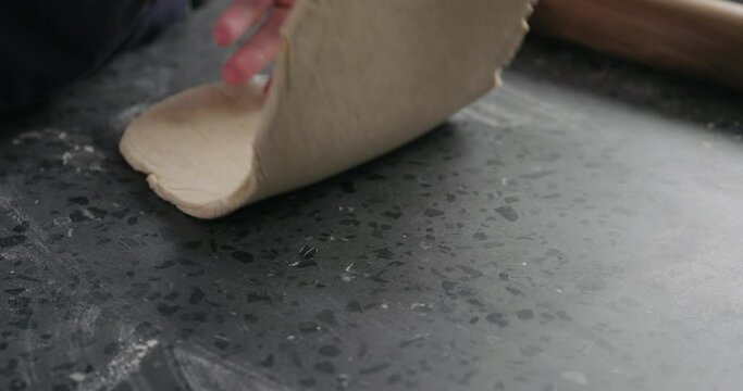 Slow motion man rolling dough on concretre countertop