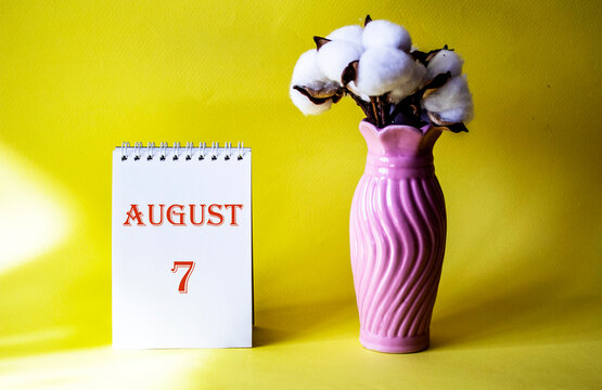 Calendar with text 7 august on yellow background and with a vase of flowers
