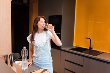 Gorgeous young girl drinking water from glass at home