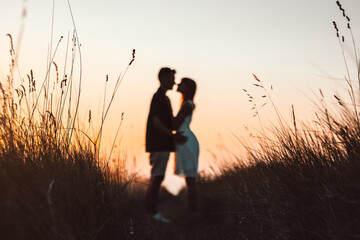 Romantic couple in love having a romantic kiss at sunset on a wheat field. Blurred effect