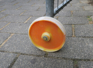 orange painted plastic wheel on a fence at the sidewalk