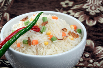 bowl of cooked basmati garnished with chopped vegetables in even lighting