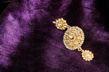 Close up portrait jewellery  earrings on purple/magenta colour fabric