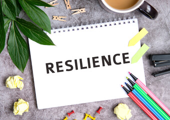 Resilience on a notebook with a cup of coffee, compressed sheets, crayons, stapler