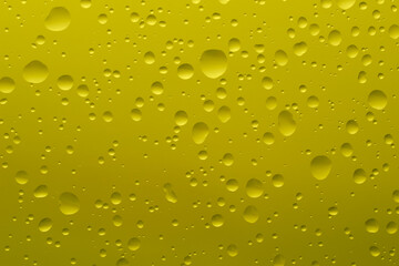 Drops of water of different shapes and sizes on a yellow background