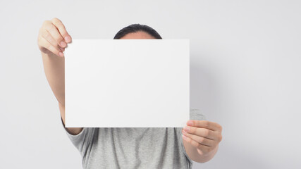 Male's hands is holding the A4 paper and wear gray t shirt and standing on white background.