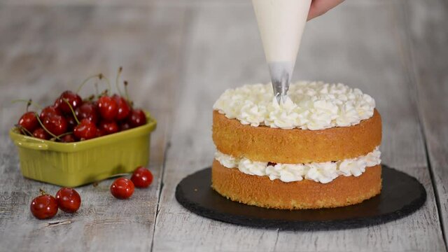 Decorating a cherry cake with cream from the pastry bag.