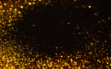 Sparkling gold glitter on a black background, magic abstract background. Round frame made of gold particles,