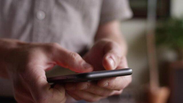Close up on the hands of a man using a smartphone
