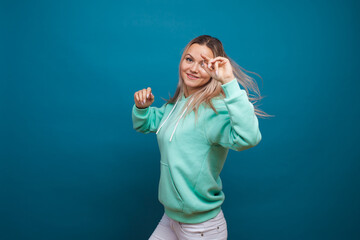 Fototapeta premium Happy girl smiling, portrait in Studio on blue background. Positive young blond woman
