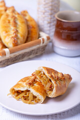Pies (pirozhki) with cabbage. Homemade baking. Traditional Russian and Ukrainian cuisine. In the background is a basket with pies. Close-up.