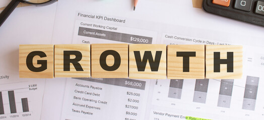 Wooden cubes with letters on the table in the office. Text GROWTH. Financial concept.
