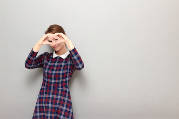 Portrait of happy girl making heart gesture with hands over face