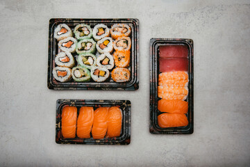 stock photography assorted rice sushi inside three tupper black reusable tray on gray background