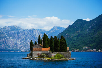 Fototapeta premium Widok na górskie jezioro, góry, jachty rekreacyjne. Wyspa na środku jeziora. Słynna zatoka przypominająca fiord, na skalistych brzegach której znajdują się Kotor i Perast. Zatoka Boko Kotor, zatoka.