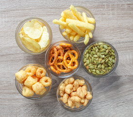 Top view of different types of snacks on wooden table. Crisps and treats from above.