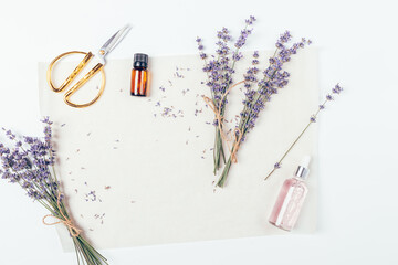 Flat lay lavender flowers next to essential oil and scissors