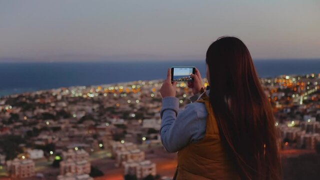 Woman take picture of the sea by smartphone in the evening. Woman stay on top of the mountain and looking Into Horizon, full hd