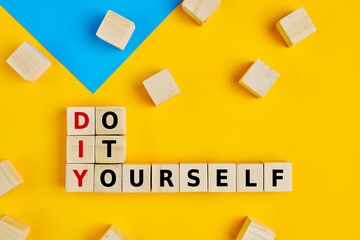 DIY and do it yourself words written on wooden blocks on yellow background