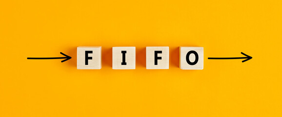 The business abbreviation fifo (first in first out) written on wooden blocks with directional arrows - obrazy, fototapety, plakaty