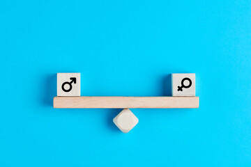 Concept of gender equality. Wooden blocks with male and female symbols on a balanced seesaw