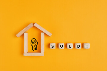 Concept of selling or buying a house or real estate. House made of wooden blocks and sold word on...