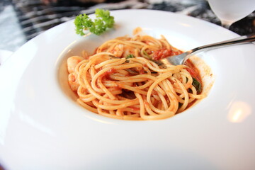 Spaghetti with shrimp in white disc on marble table