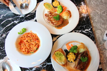 Beef steak  and Spaghetti with corn bread, broccoli and gravy in white disc on marble table