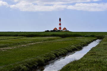 Fototapeta na wymiar The famous lighthouse in Westerhever with a great sky and clouds