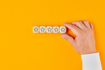 Hand of a businessman placing five star rating icon on wooden cubes in a row