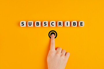 Male hand pressing subscription button with the word subscribe written on wooden blocks. Concept of...