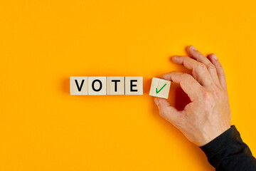 Concept of voting yes or positive vote. Male hand placing wooden cube with check mark yes symbol...