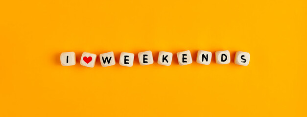 I love weekends text written on wooden cubes against yellow background. Weekend concept.
