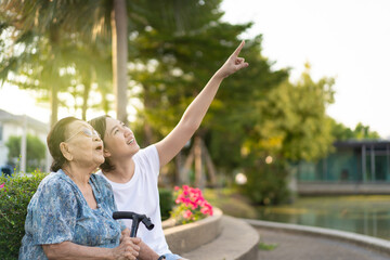 Asian woman taking care of elder Asian woman, age almost 90 years old in a park close up with copy...