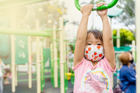 young asian girl wearing mask playing outdoor hanging having fun