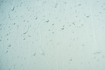 Rain drops on glass with dark storm skies background.