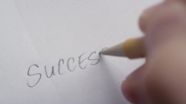 "Success" being written on white paper with a mechanical pencil