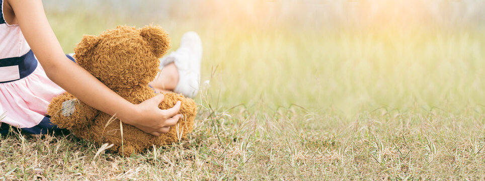 Banner Happy Child hug teddy bear in green park playground. Teddy bear best friend for little girl. Autism happy playing together on playground in happiness family feel love warm hugs with copy space
