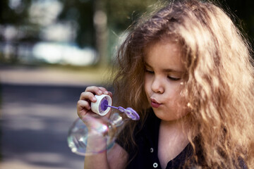 curly little girl blowing bubbles