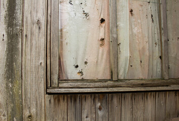 An old wooden wall with a window and a curtain with holes in it